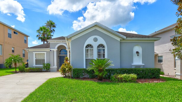 A residential house with a front yard, a palm tree, and a clear sky. - Private Pool Paradise, Soaring Ceilings, Open Spaces & Fl Resort-Style Charm (Davenport)