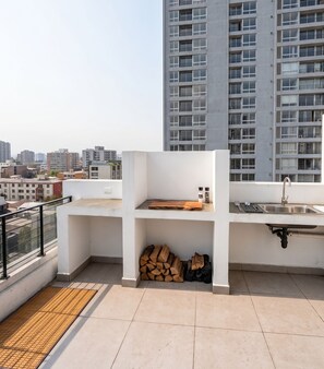 Eine Dachterrasse mit integrierter Küchenzeile, inklusive Spüle und Schneidebrett.