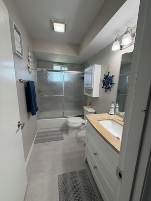 Une salle de bain équipée d’une douche, de toilettes, d’un lavabo et d’un miroir orné d’un motif de roue de navire.