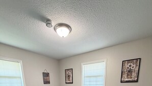 A bedroom with a bed, bedside tables, a dresser, and a window with blinds. - Shoreline Haven (Erie)