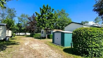 Un terrain de camping comprenant plusieurs mobil-homes, un chemin de gravier et des arbustes verdoyants.