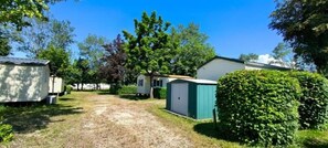 A campsite with multiple mobile homes, a gravel path, and green shrubbery. - Camping Del Padel (Les Avenières Veyrins-Thuellin)