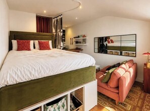 Ein Schlafzimmer mit Bett, Sofa, Spiegel und Lampe.