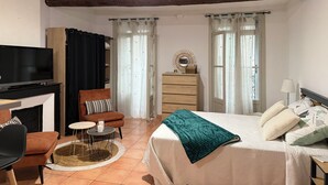 Una habitación con cama, televisión, escritorio y silla.