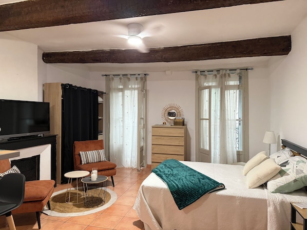 Una habitación con cama, televisión, escritorio y silla.