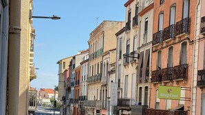 Una calle con edificios de varios pisos, cielo despejado y un letrero de farmacia.