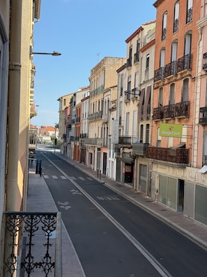 Una calle con edificios de varios pisos, cielo despejado y un letrero de farmacia.