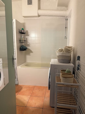 Un baño con bañera, lavadora y tendedero.