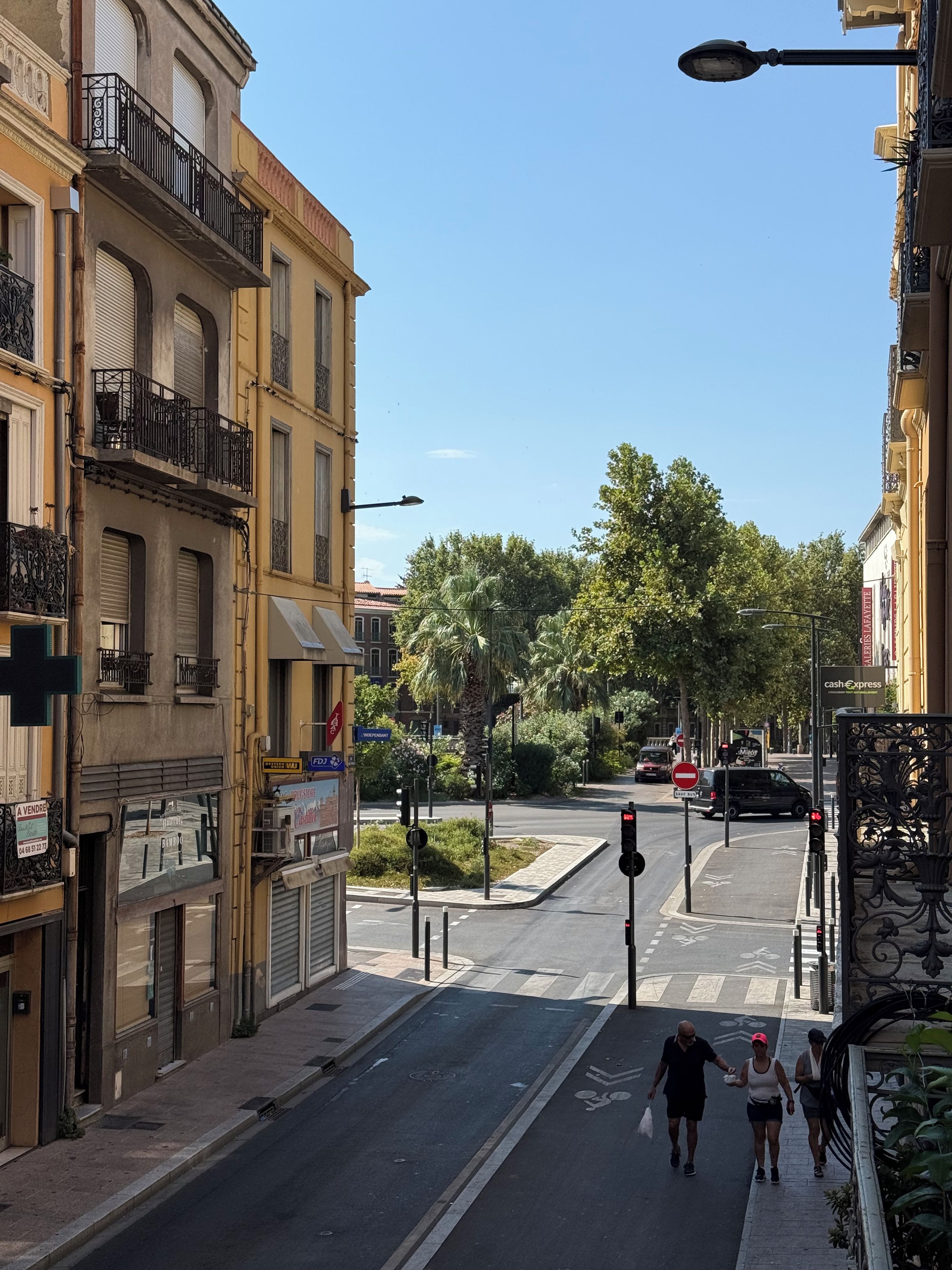A street view with buildings, a pedestrian crossing, and a clear sky.