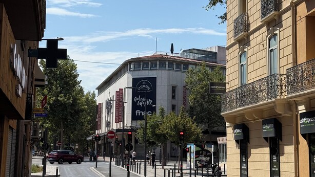 Una calle con edificios, cielo despejado y un paso de peatones.