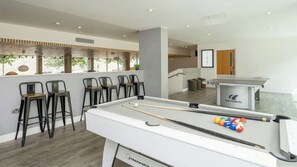 A pool table with cues and balls, bar stools, and a billiards table branded 'Cornilleau' in a room with a modern design. - Student Only Palamon Court (Canterbury)