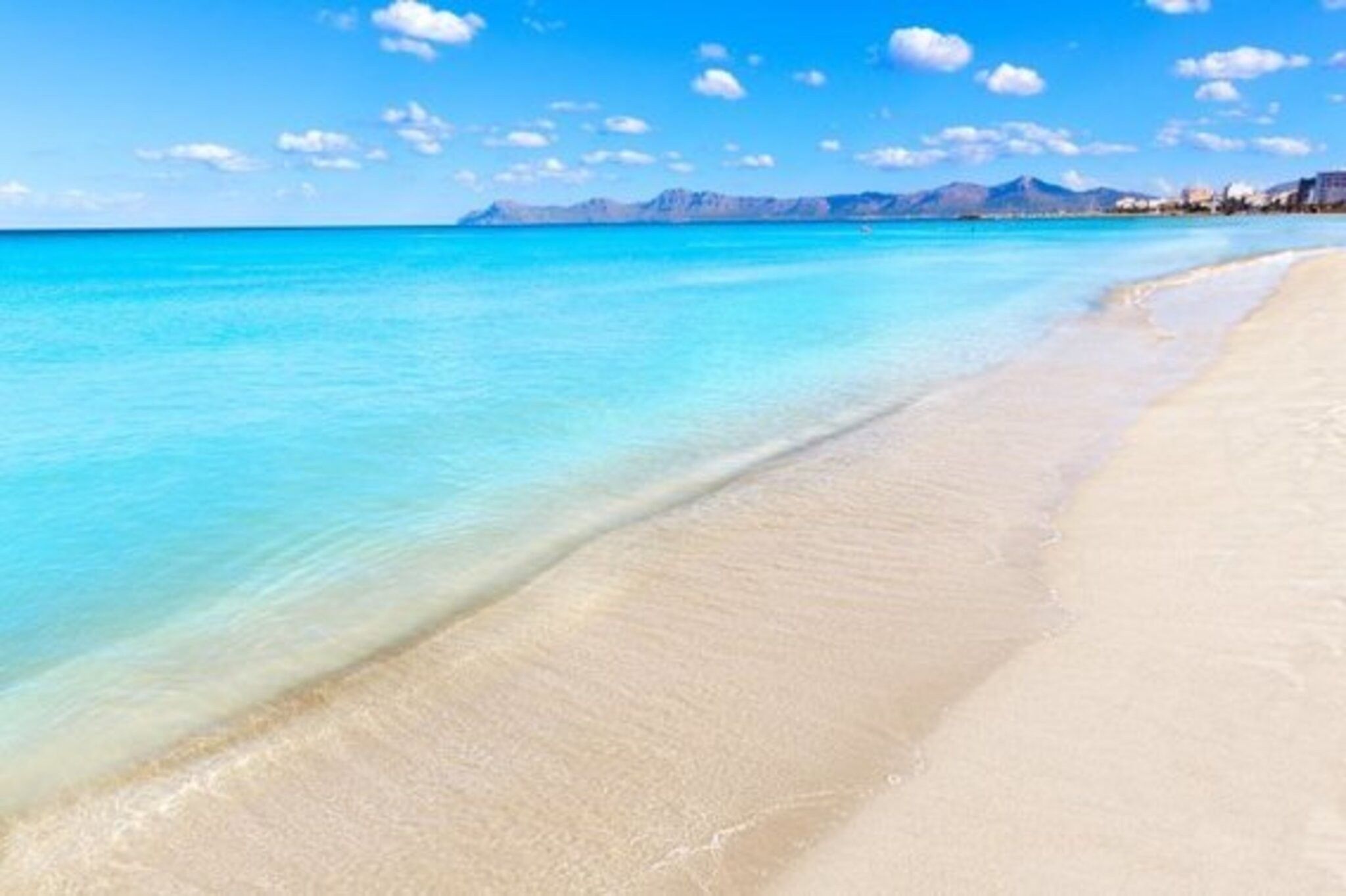 Ein Strand mit klarem türkisblauem Wasser und einem Sandufer.