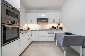 A modern kitchen with white cabinets, stainless steel appliances, and a tiled backsplash.