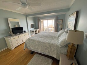 Ein Schlafzimmer mit einem Bett, einem Fernseher, einer Kommode und einem Fenster mit Blick.