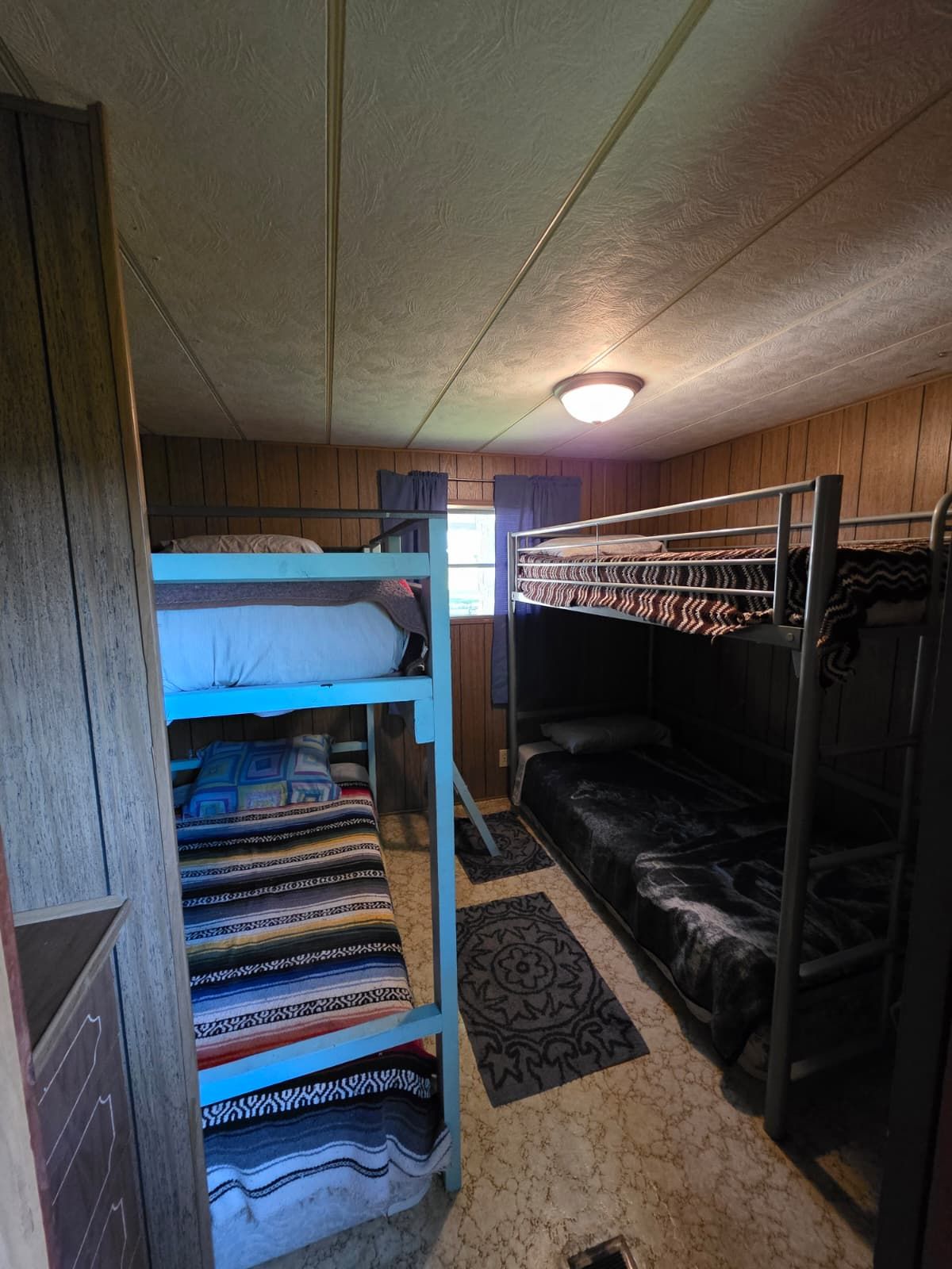 A bunk bed room with a wooden ceiling and a single light fixture.