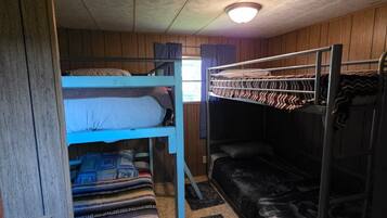 A bunk bed room with a wooden ceiling and a single light fixture.