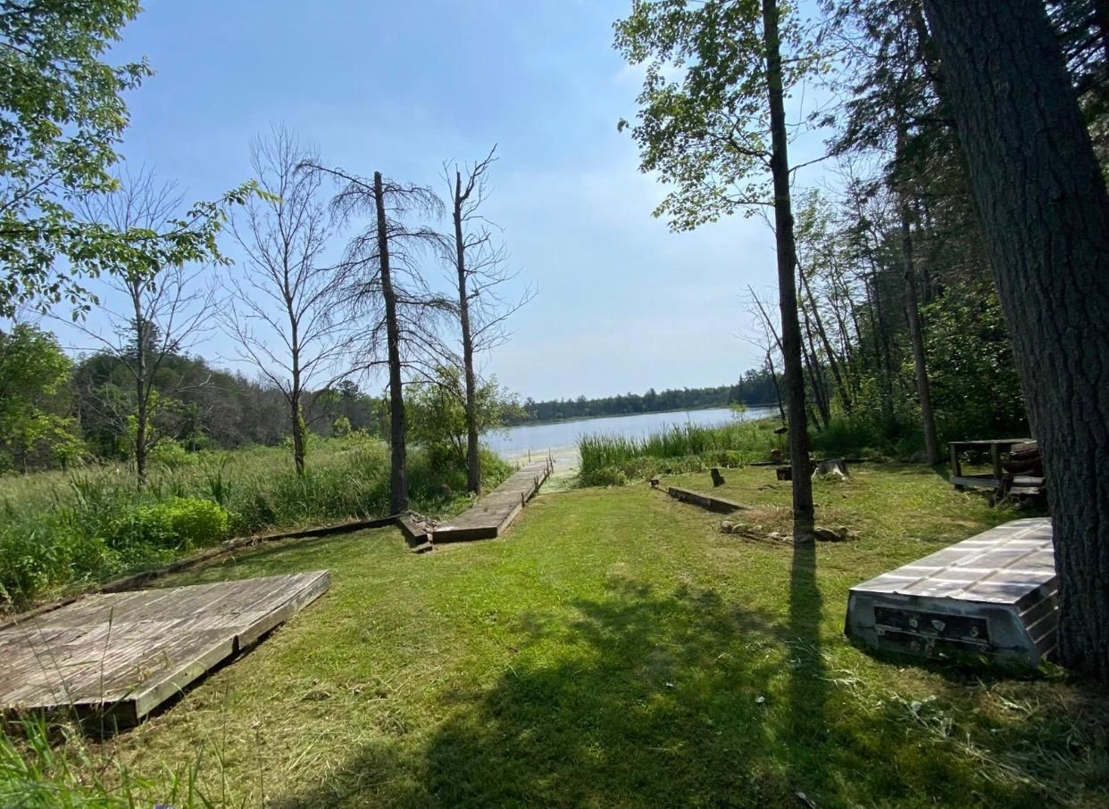 Leirintäalue, jossa on puinen kävelyreitti, joka johtaa järvelle. Alue on metsän ja nurmialueiden ympäröimä.