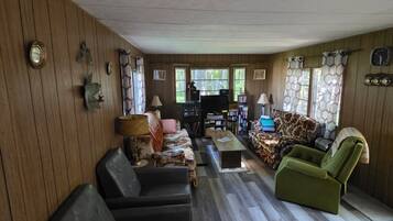 A living room with a sofa, chairs, a coffee table, and a television.