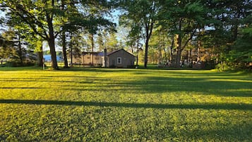 A grassy field with a house and trees in the background.