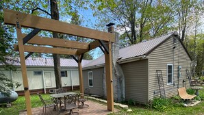 Takapihalla on pergola, terassipöytä ja tuoleja. Taustalla näkyy pieni varasto ja talo.