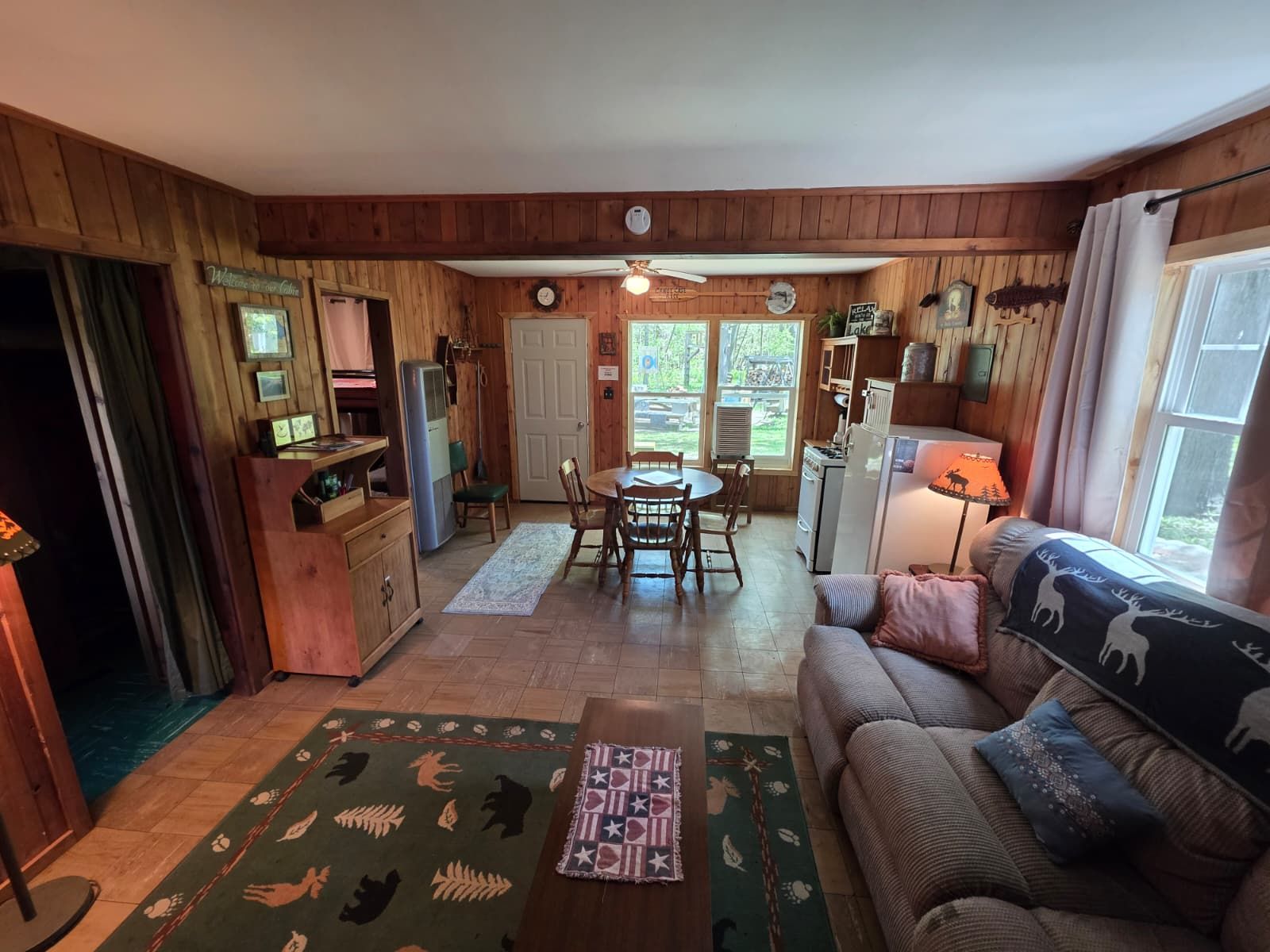 A cabin interior with a dining area, kitchen, and living room.