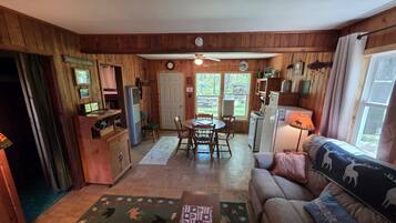 A cabin interior with a dining area, kitchen, and living room.