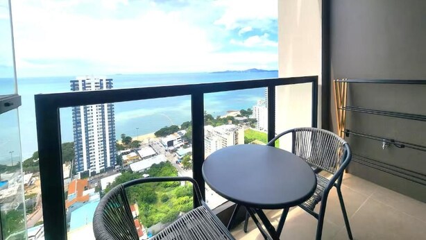 Un balcon avec une table et des chaises, offrant une vue sur le paysage urbain et la mer.
