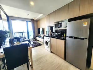 A modern kitchen with a washing machine, microwave, and refrigerator. - The Panora Condominium Pattaya (Pattaya City)
