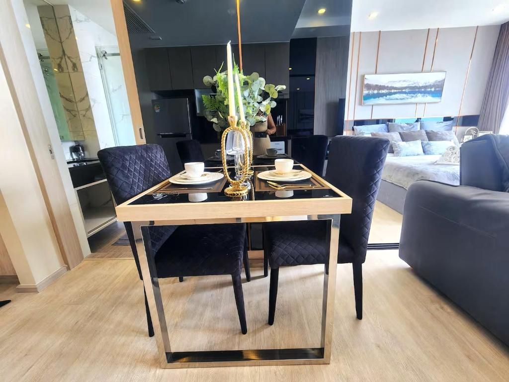 Un comedor moderno con una mesa dispuesta para cuatro comensales, una silla tapizada oscura y un diseño minimalista.