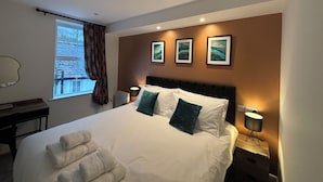A hotel room with a large bed, a desk, and a window with curtains. - Braithwaite House Rooms (Keswick)