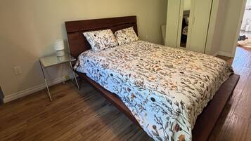 Une chambre à coucher avec un lit en bois, une table de chevet, une armoire et un luminaire au plafond.