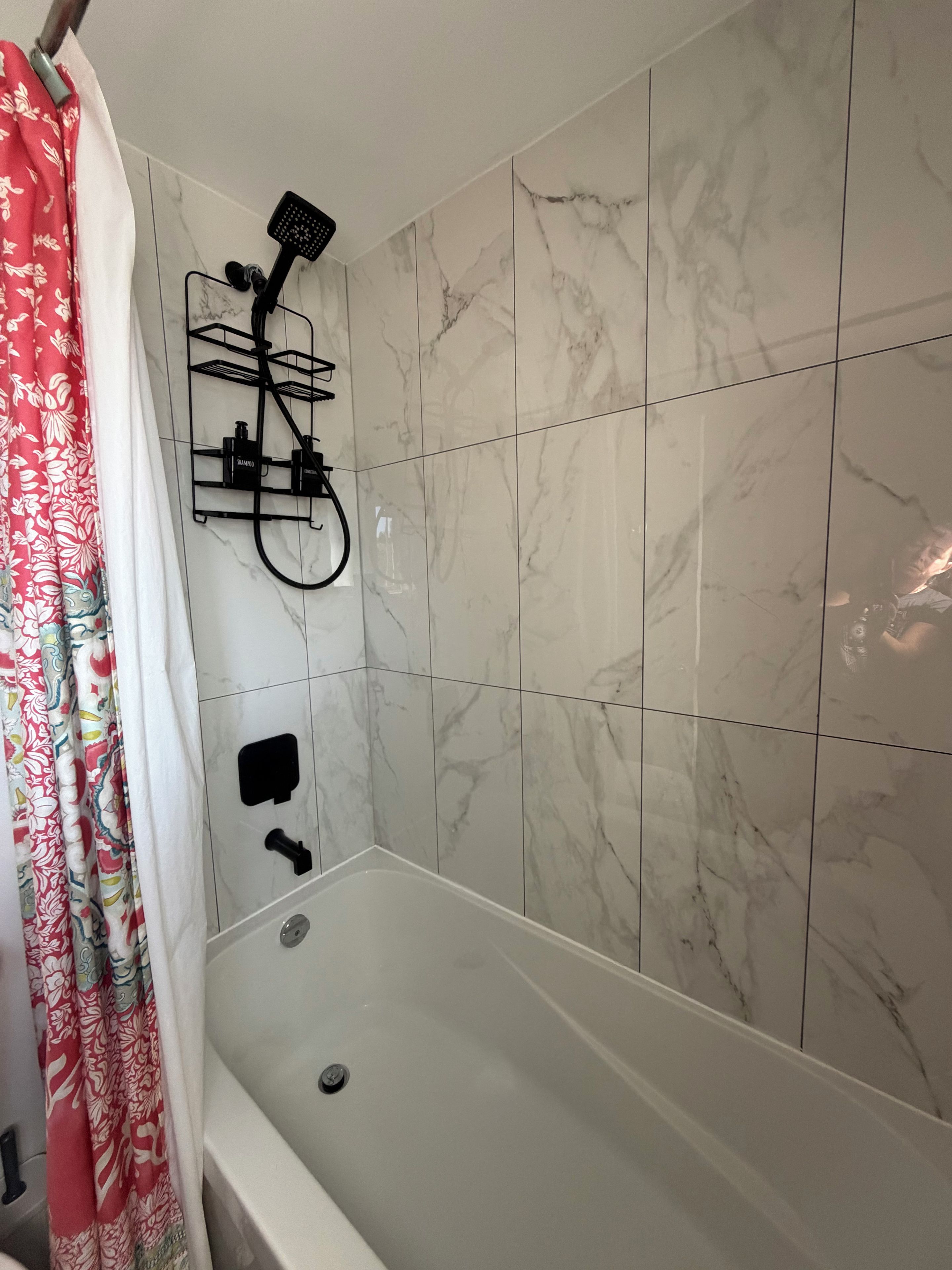 Et badeværelse med bruser, toilet og badekar.