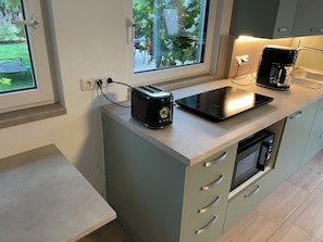 Eine Küche mit Toaster, Kaffeemaschine und einem Fenster mit Gartenblick.