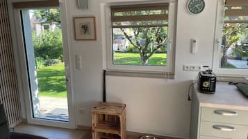 A room with a sliding glass door, a small wooden stool, a pet feeding station, and a toaster on the counter.