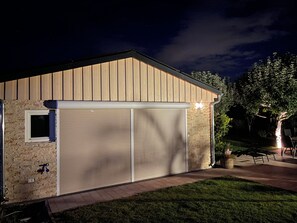 A building with a garage door, a small window, and a brick wall.