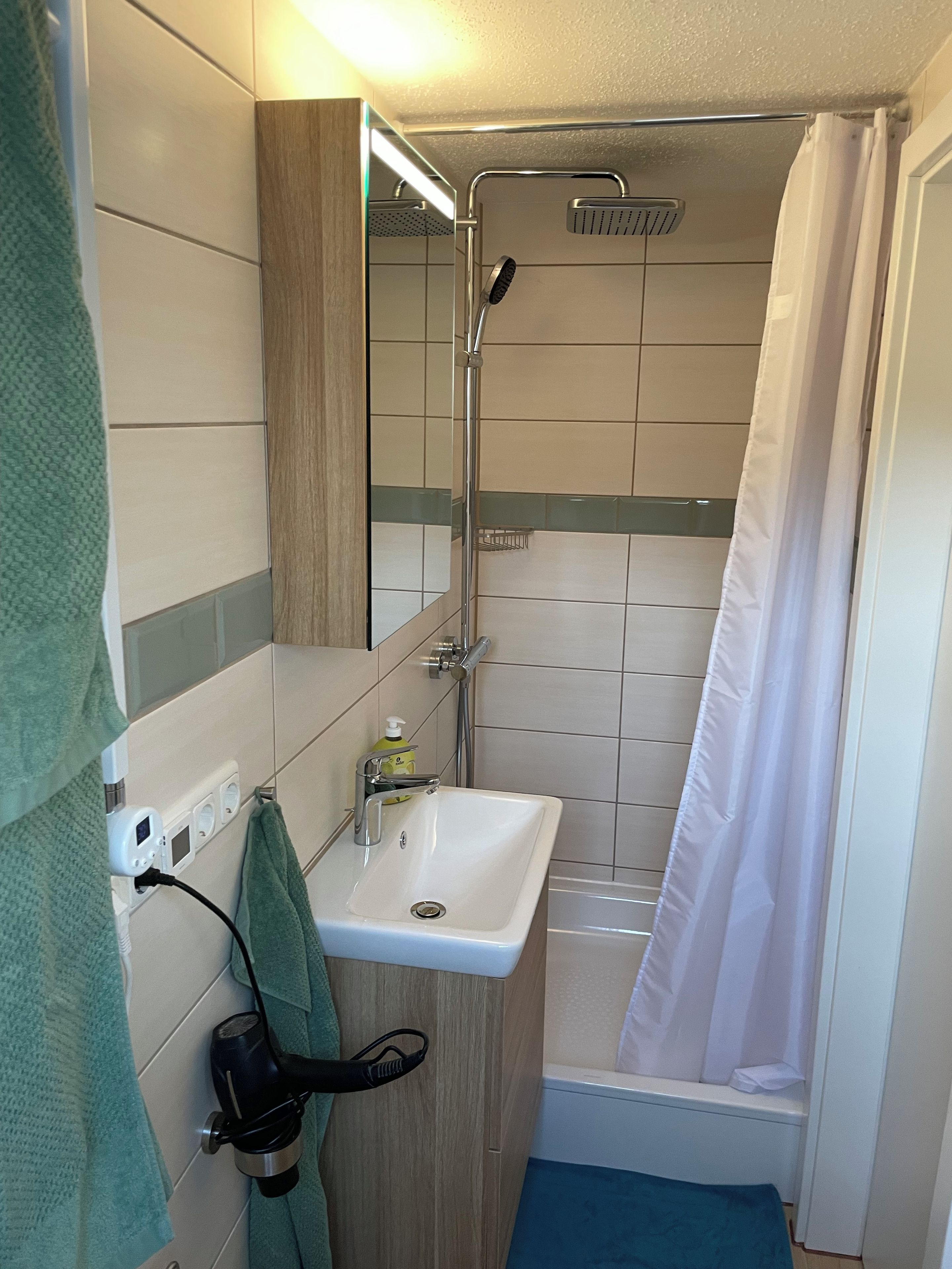 A bathroom with a shower, a sink, and a towel rack.