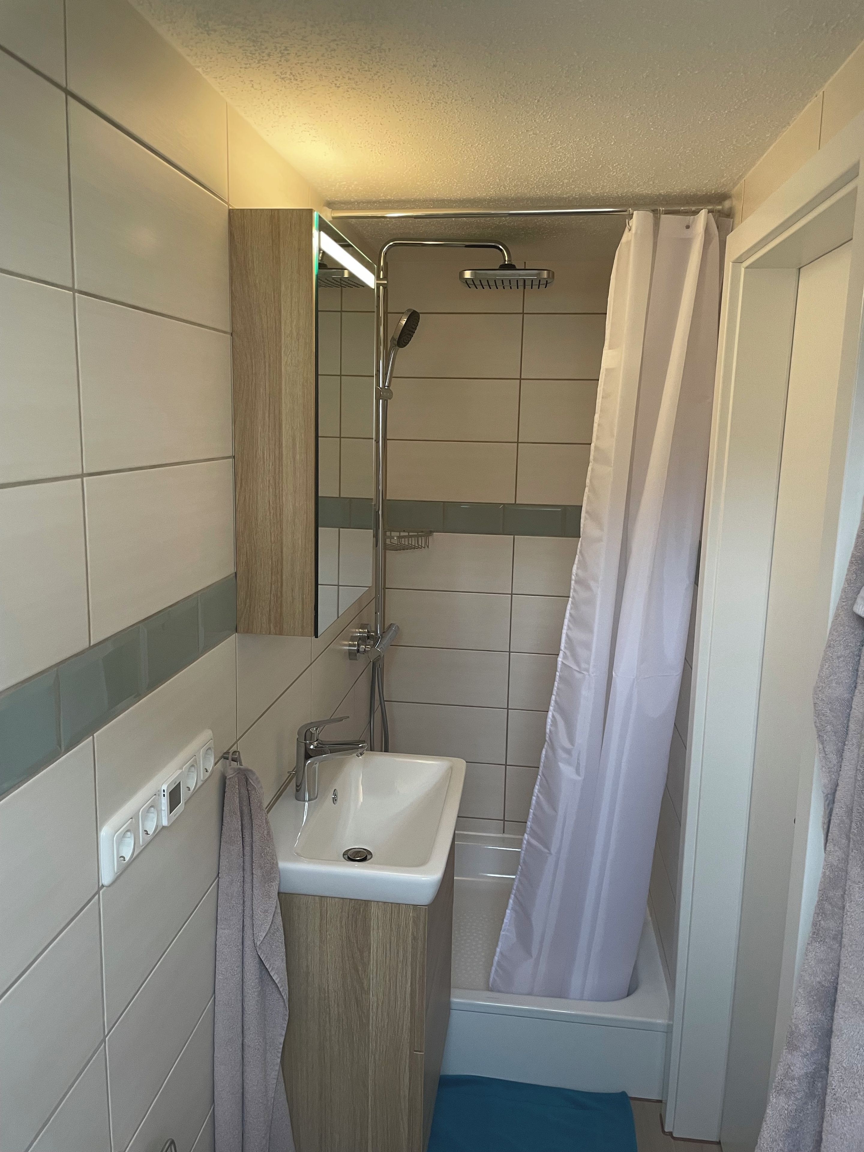 Ein Badezimmer mit Dusche, Waschbecken und Handtuchhalter.