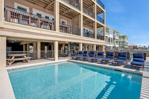 A hotel with a pool, multiple balconies, and outdoor seating. - Beach Estate (Gulf Shores)