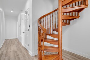 A wooden spiral staircase with a handrail and a landing. - Beach Estate (Gulf Shores)