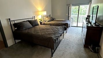Een slaapkamer met twee bedden, een plafondventilator, een dressoir en uitzicht door een schuifdeur.