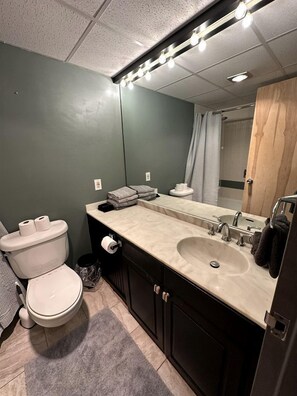 A bathroom with a toilet, sink, mirror, and towel rack.