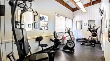 Une salle de sport équipée de matériel d’exercice, d’un tapis de course et d’un vélo d’appartement.