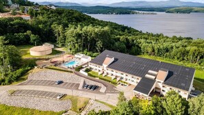 Un hotel con piscina, area parcheggio e vista su un lago e montagne.