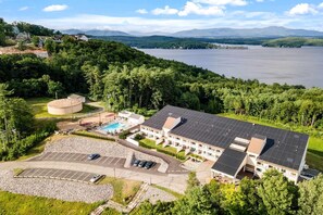 Et hotel med swimmingpool, parkeringsplads og udsigt til sø og bjerge.