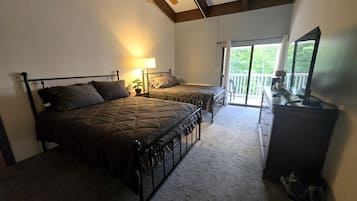 A bedroom with two beds, a ceiling fan, a dresser, and a sliding glass door leading to a balcony.