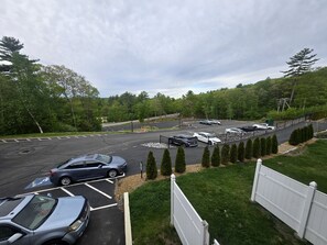A parking lot with multiple cars and a fenced area with trees.