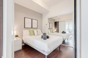A modern bedroom with a large bed, bedside tables, a mirror, and artwork on the wall. - Elegant & Spacious 2BR1BA Downtown Condo w/Parking (Toronto)