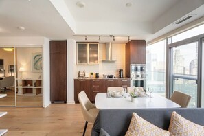 A modern kitchen with a dining area, large windows, and a city view. - 1BR Condo with City View, Near CN Tower & Parking (Toronto)