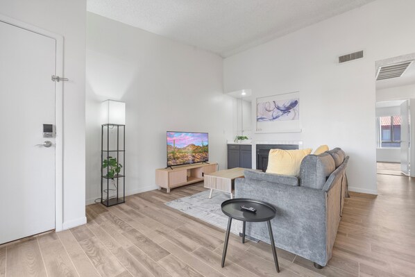 Uma sala de estar moderna com sofá, televisão e uma pequena mesa.