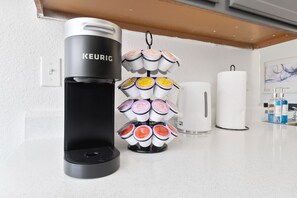 Máquina de café Keurig com suporte para caneca e um dispensador de toalhas de papel brancas em uma bancada de cozinha.